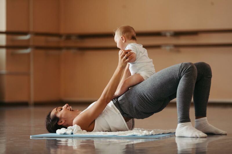 Athletic mother having fun while exercising with her baby