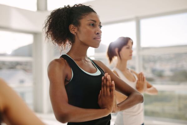 Women practice yoga together in gym