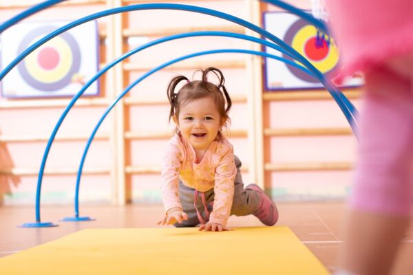 Baby girl crawling on mat in gym class. Lifestyle concept of children activity